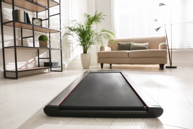 Photo of Modern walking treadmill in living room. Home gym equipment