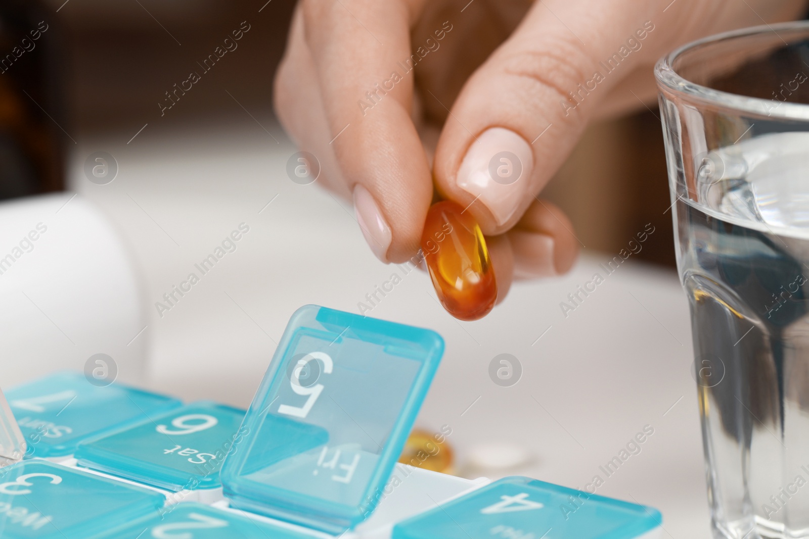 Photo of Woman taking pill from plastic box indoors, closeup