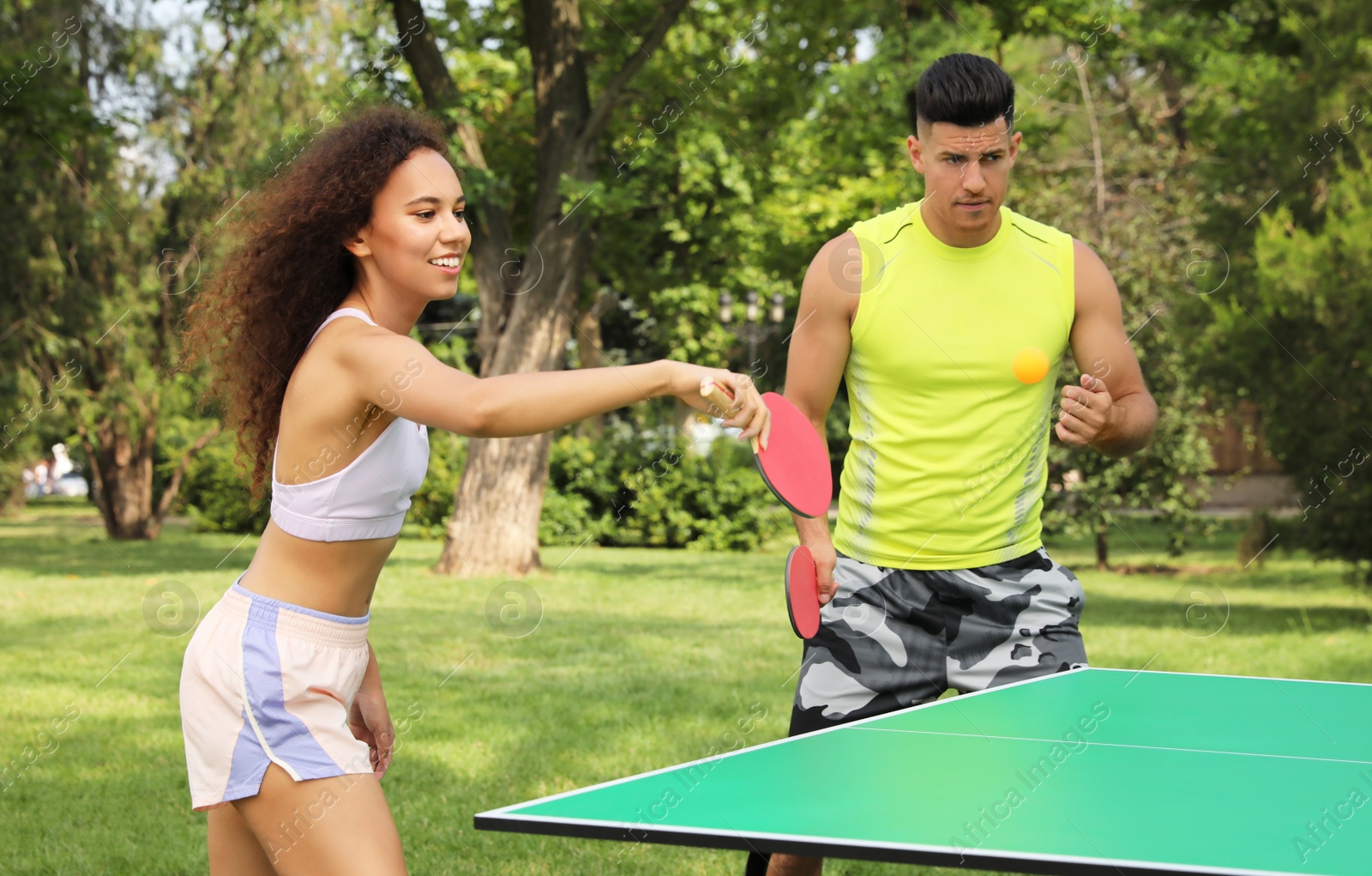 Photo of Friends playing ping pong outdoors on summer day