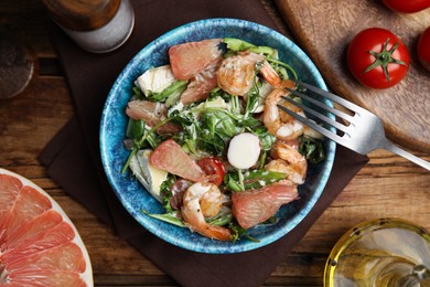 Delicious pomelo salad with shrimps served on wooden table, flat lay