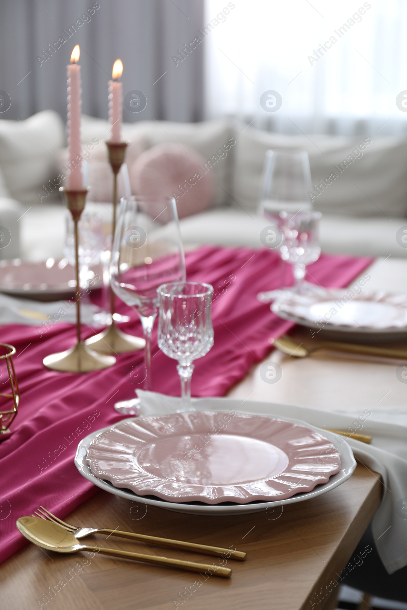 Photo of Beautiful table setting with burning candles and pink accent in dining room