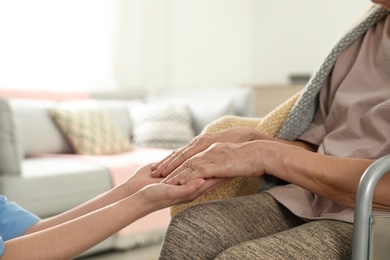 Photo of Nurse holding elderly woman's hands indoors, closeup with space for text. Assisting senior people