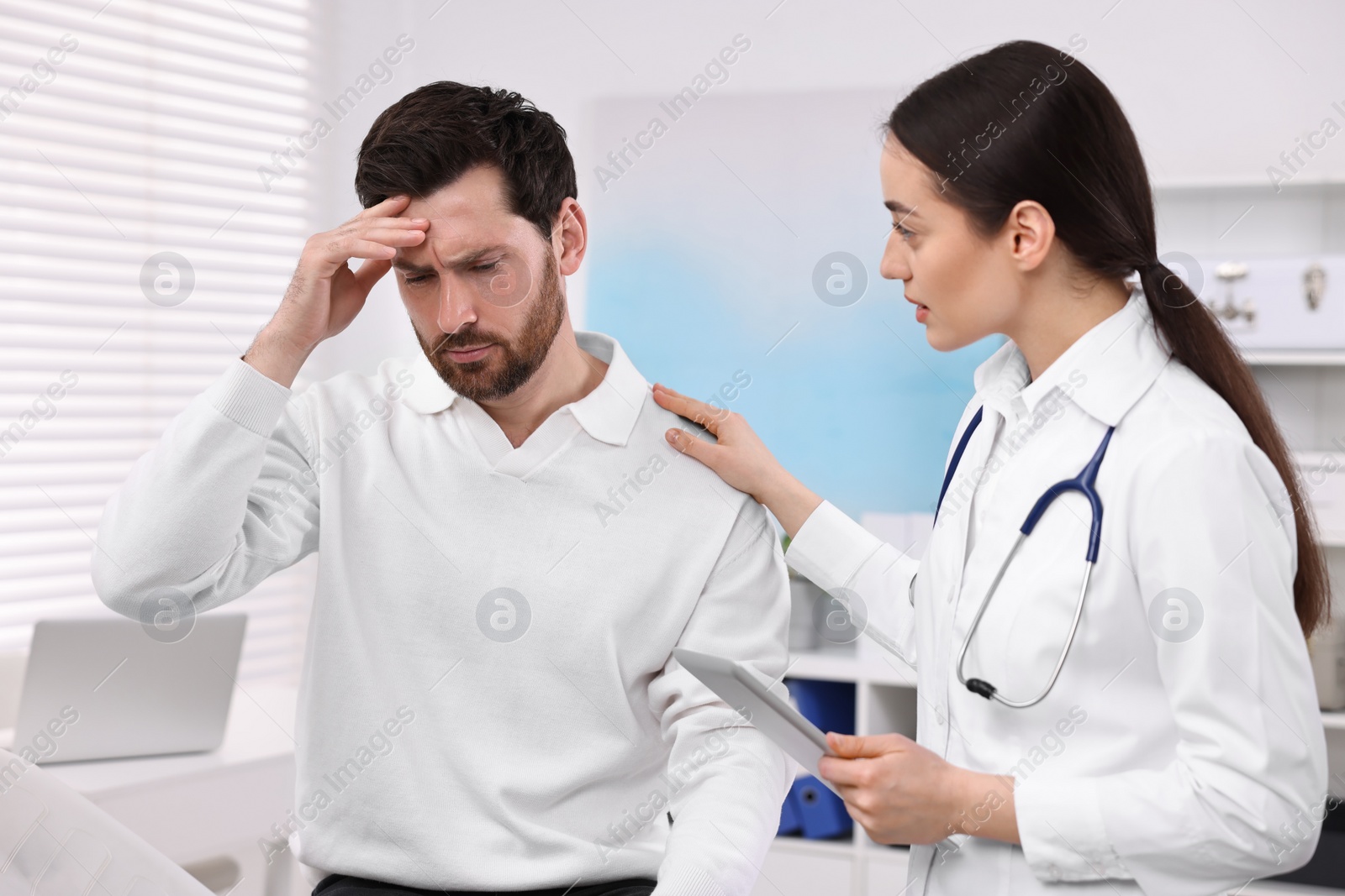 Photo of Doctor with tablet consulting patient during appointment in clinic