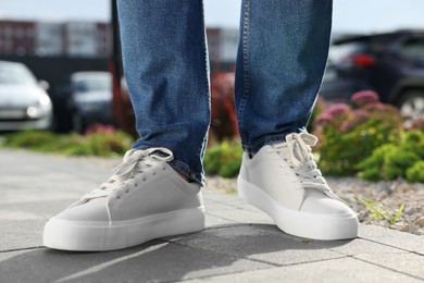 Photo of Man wearing pair of stylish sneakers outdoors, closeup