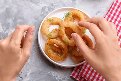 Photo of Woman eating fried onion rings at table, top view