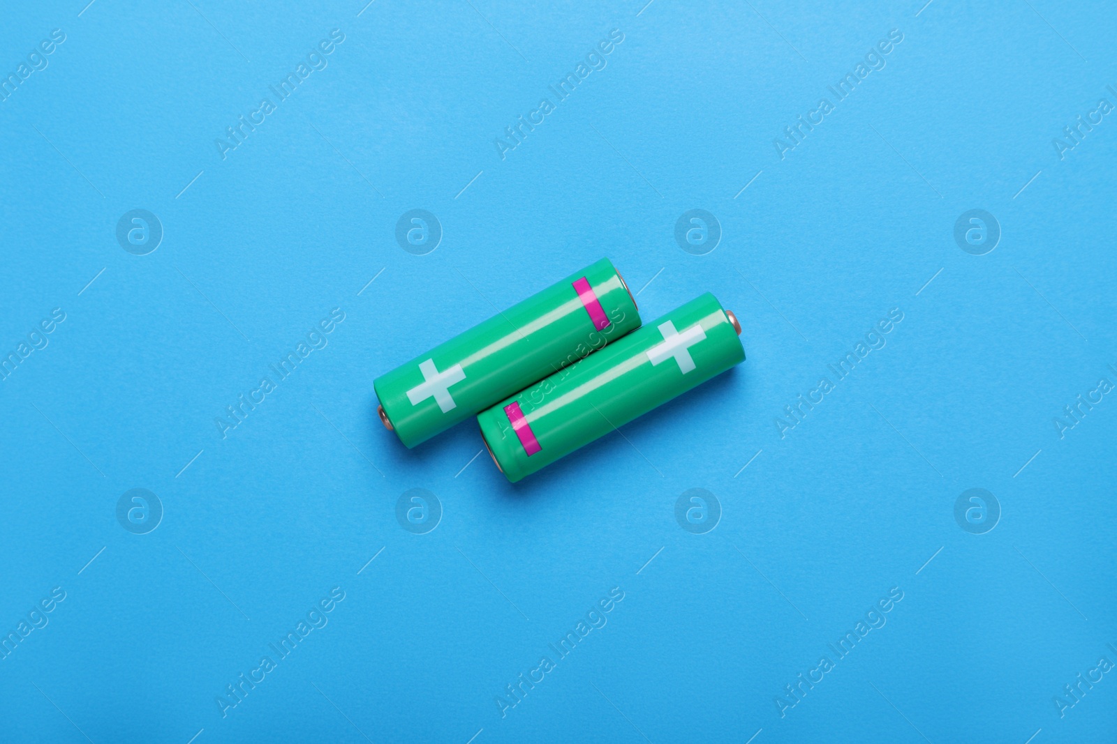 Photo of New AA size batteries on light blue background, flat lay