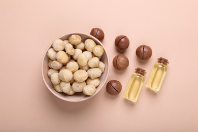 Photo of Delicious organic Macadamia nuts and cosmetic oil on beige background, flat lay
