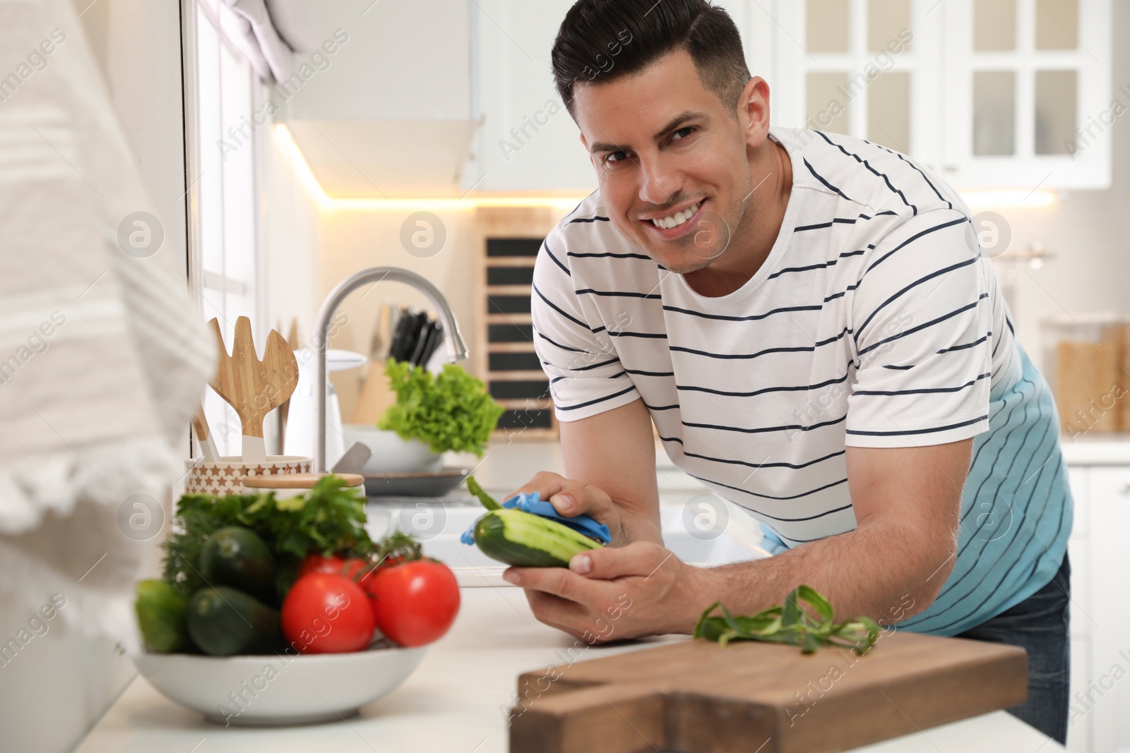 Photo of Man peeling cucumber at kitchen counter. Preparing vegetable