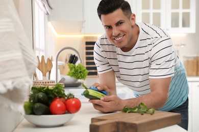 Man peeling cucumber at kitchen counter. Preparing vegetable