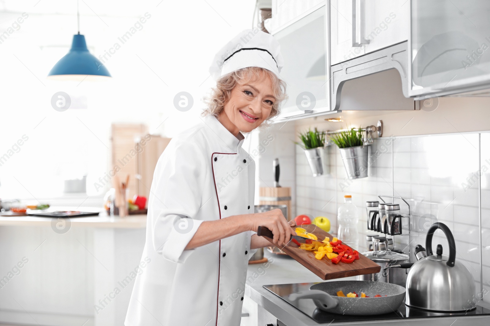 Photo of Professional female chef cooking vegetables in kitchen