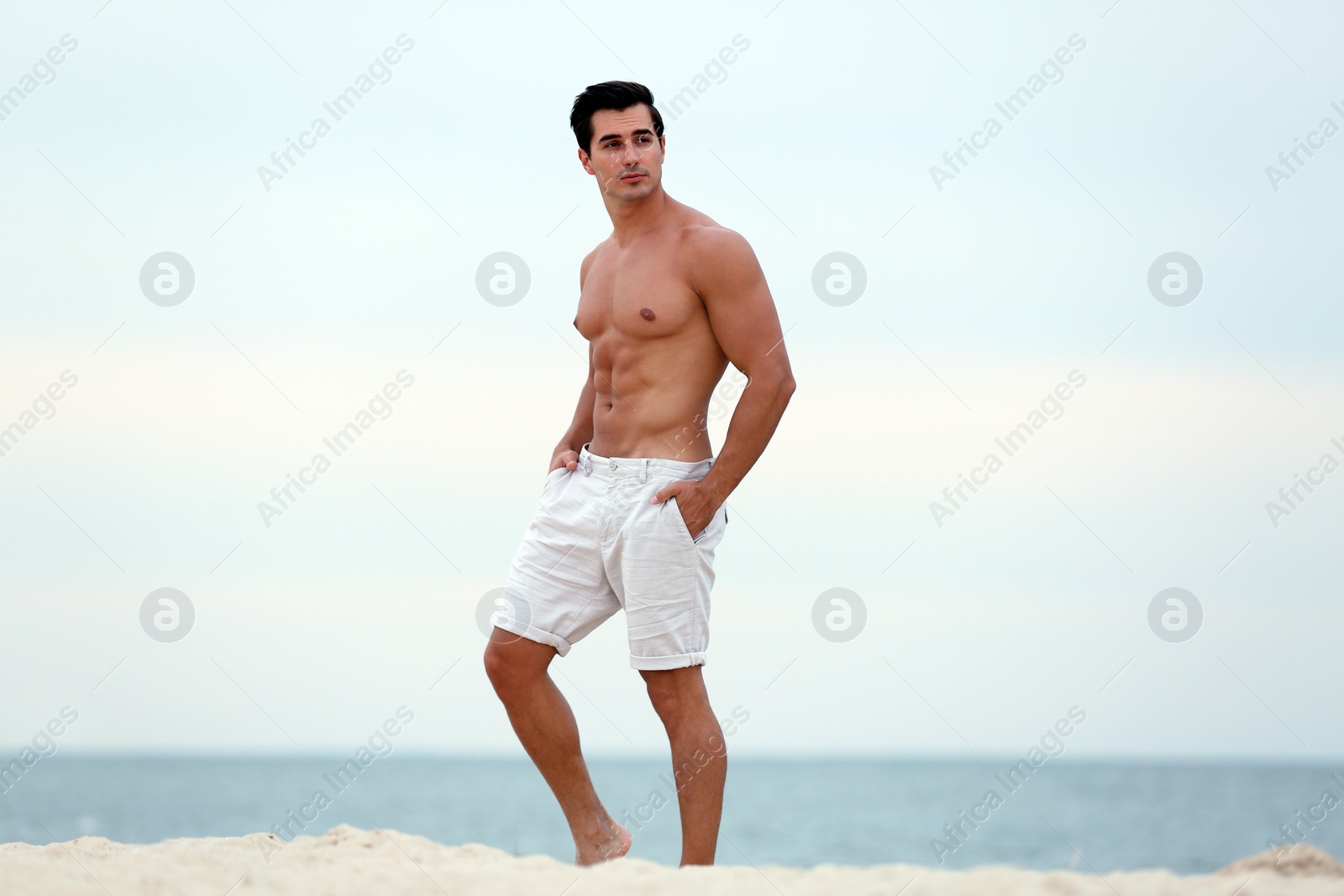 Photo of Handsome young man posing on beach near sea