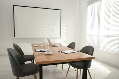 Conference room interior with wooden table and video projection screen