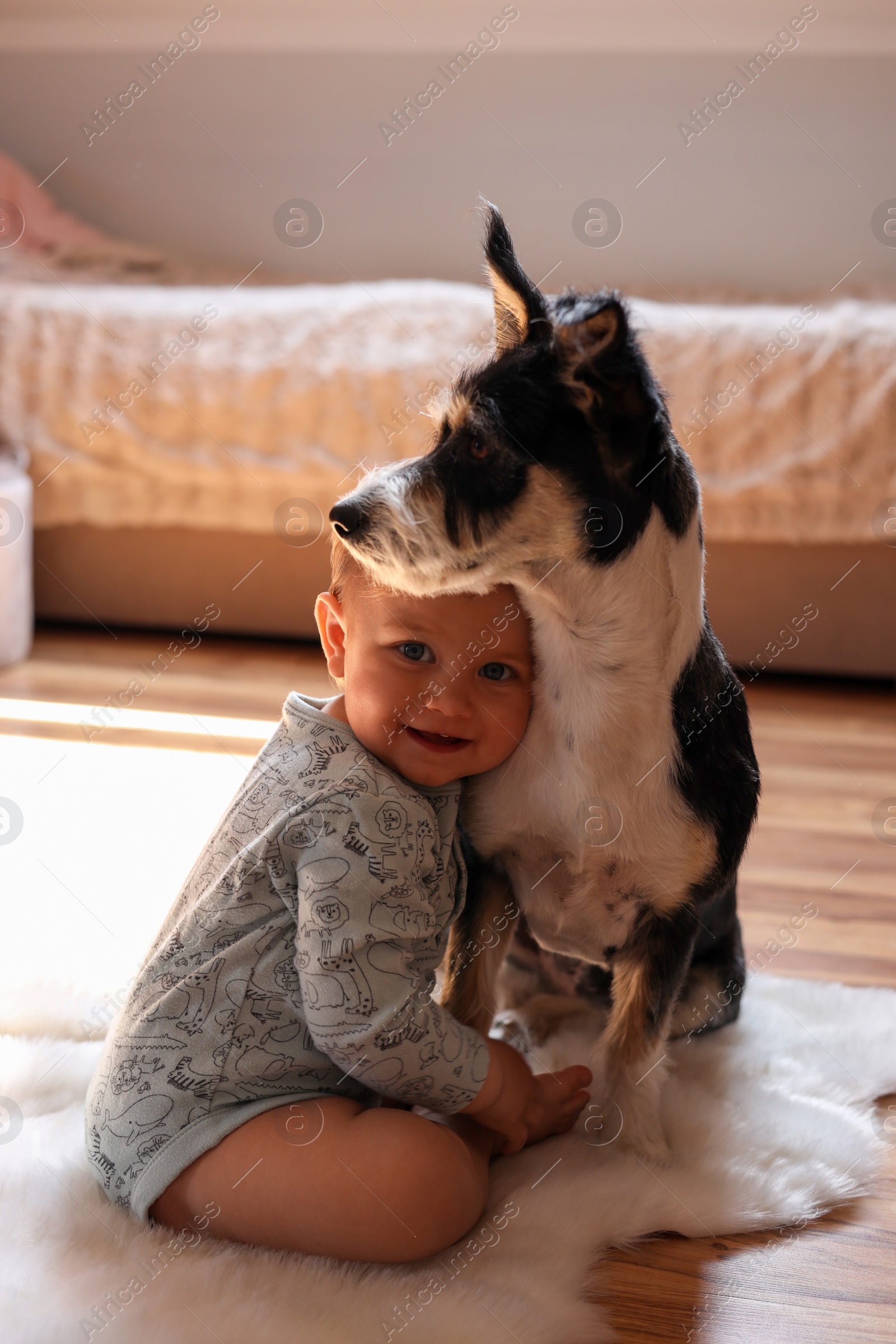 Photo of Adorable baby and cute dog on faux fur rug at home