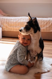 Photo of Adorable baby and cute dog on faux fur rug at home