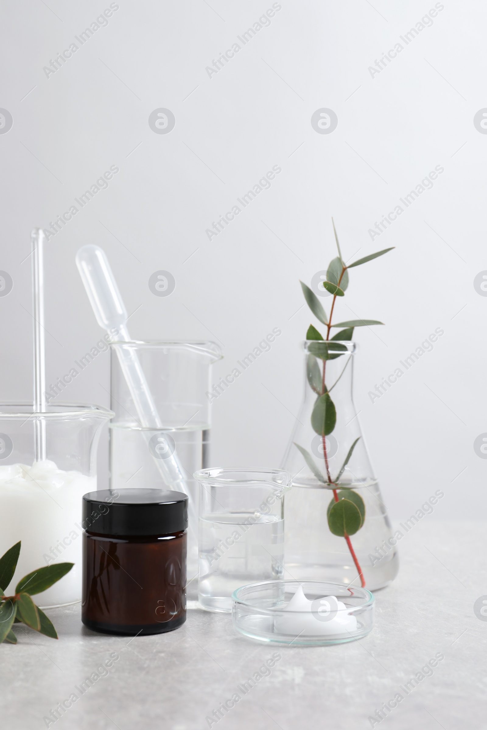 Photo of Natural ingredients for cosmetic products and laboratory glassware on white table