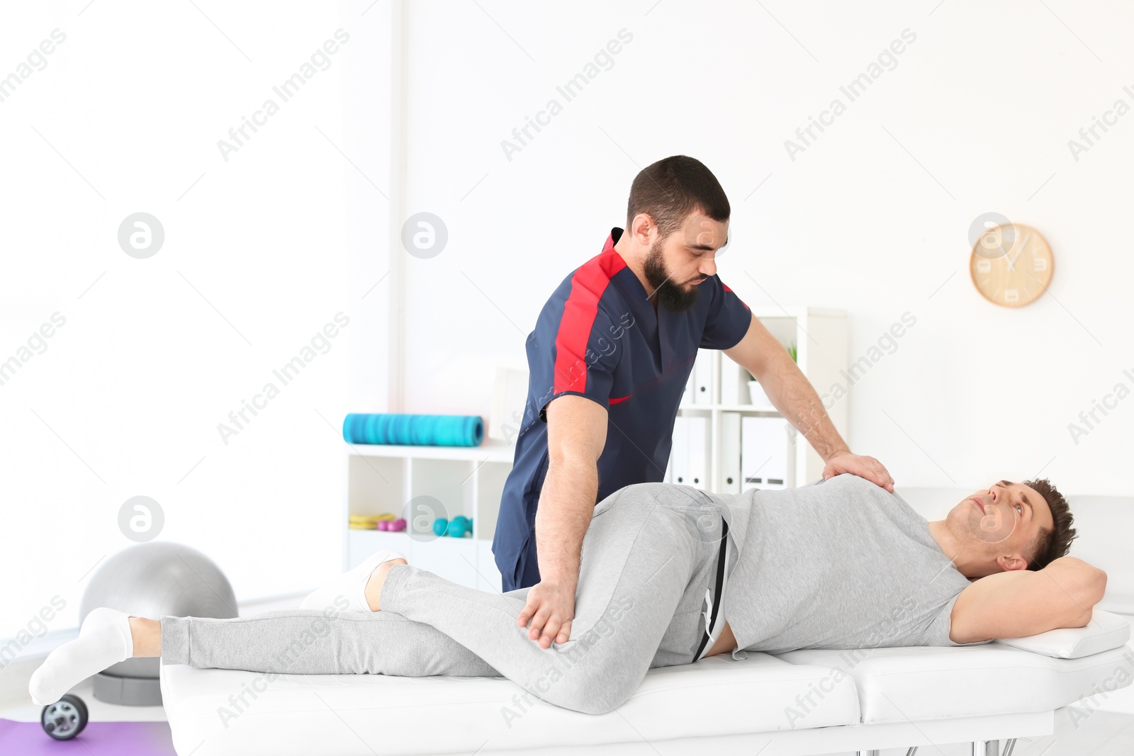 Photo of Physiotherapist working with young male patient in clinic