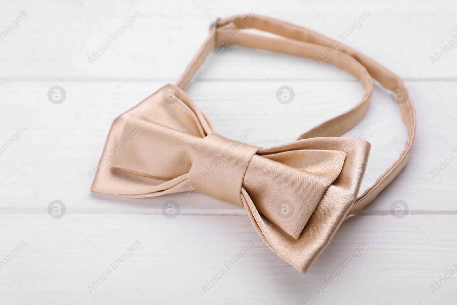 Photo of Stylish beige bow tie on white wooden table, closeup