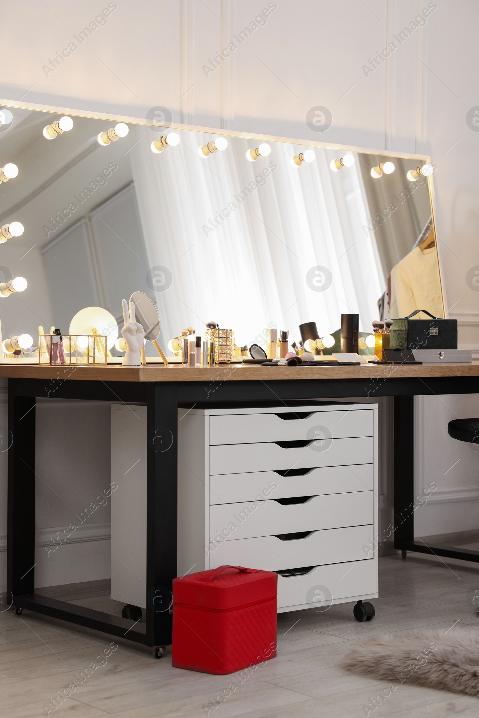 Photo of Makeup room. Stylish mirror with light bulbs and beauty products on dressing table