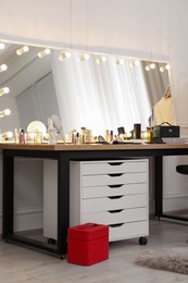 Makeup room. Stylish mirror with light bulbs and beauty products on dressing table