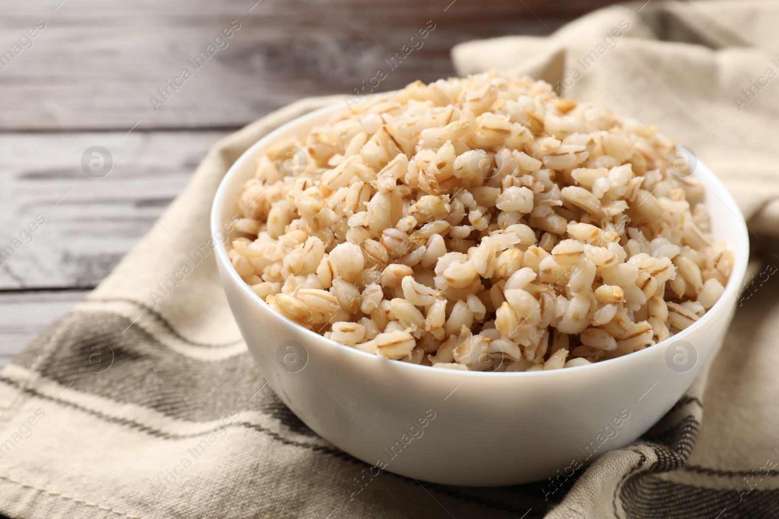 Photo of Delicious pearl barley in bowl on table, closeup