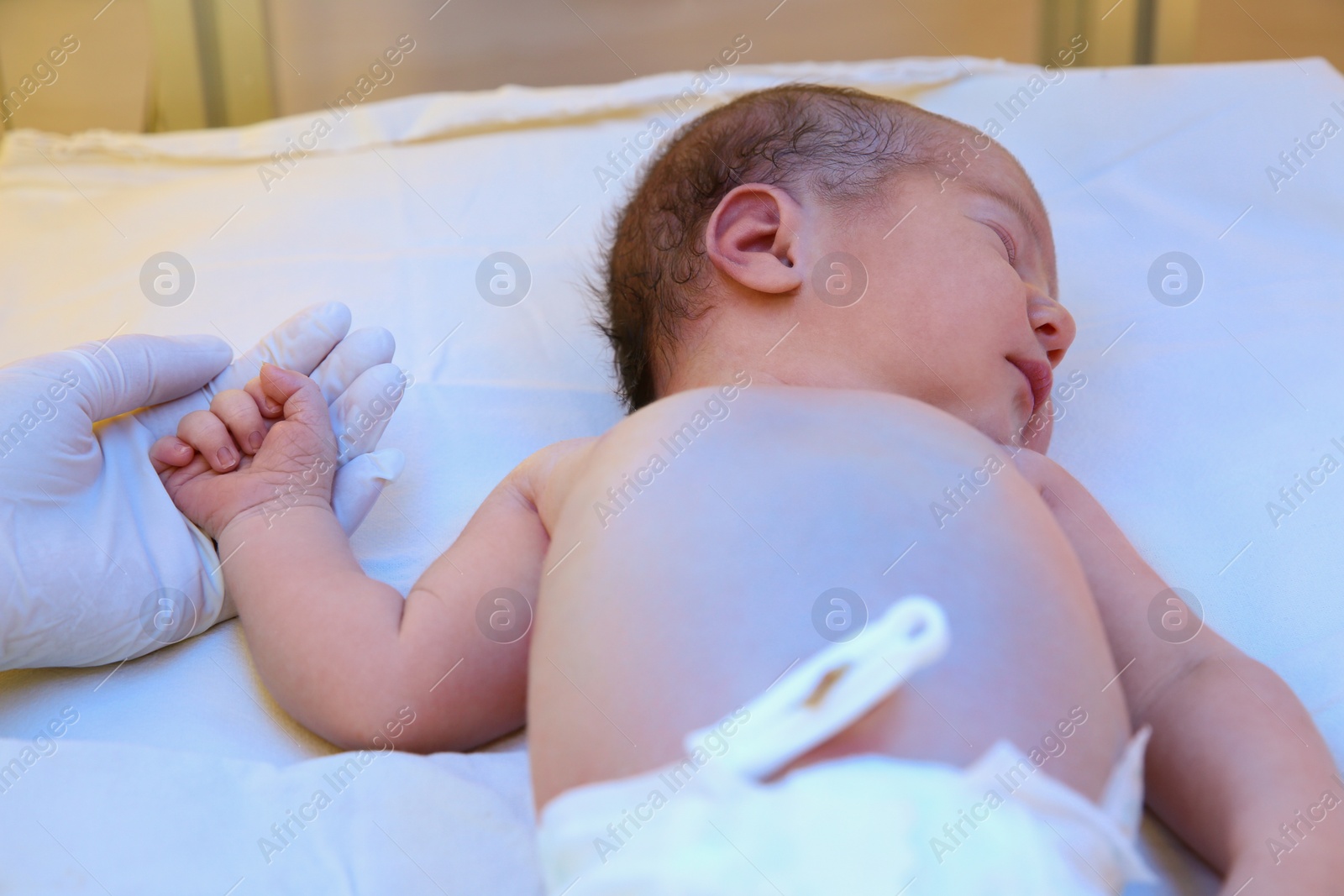 Photo of Doctor holding newborn child's hand in hospital