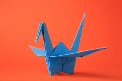 Photo of Origami art. Handmade paper crane on orange background, closeup