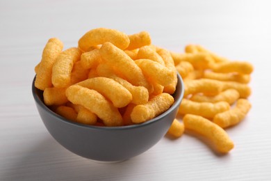 Photo of Many tasty cheesy corn puffs on white wooden table, closeup