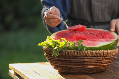 Photo of Woman holding spoon of delicious ripe watermelon outdoors, closeup. Space for text