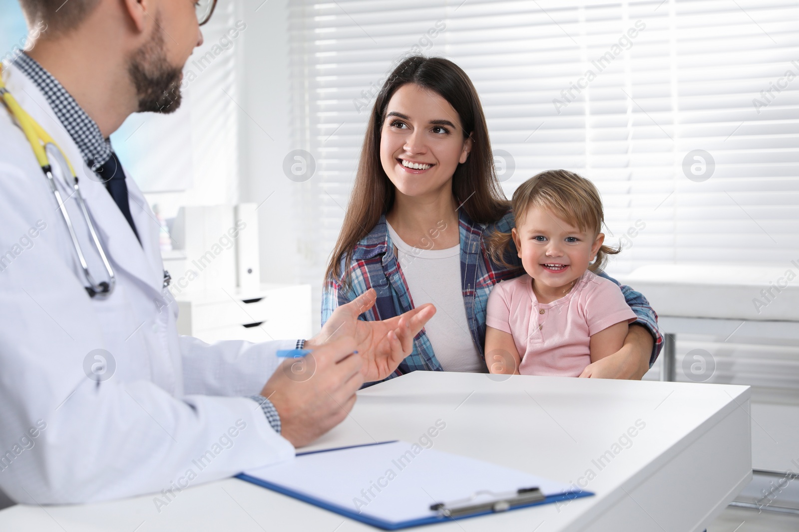 Photo of Mother and her cute baby having appointment with pediatrician in clinic. Doctor examining little girl