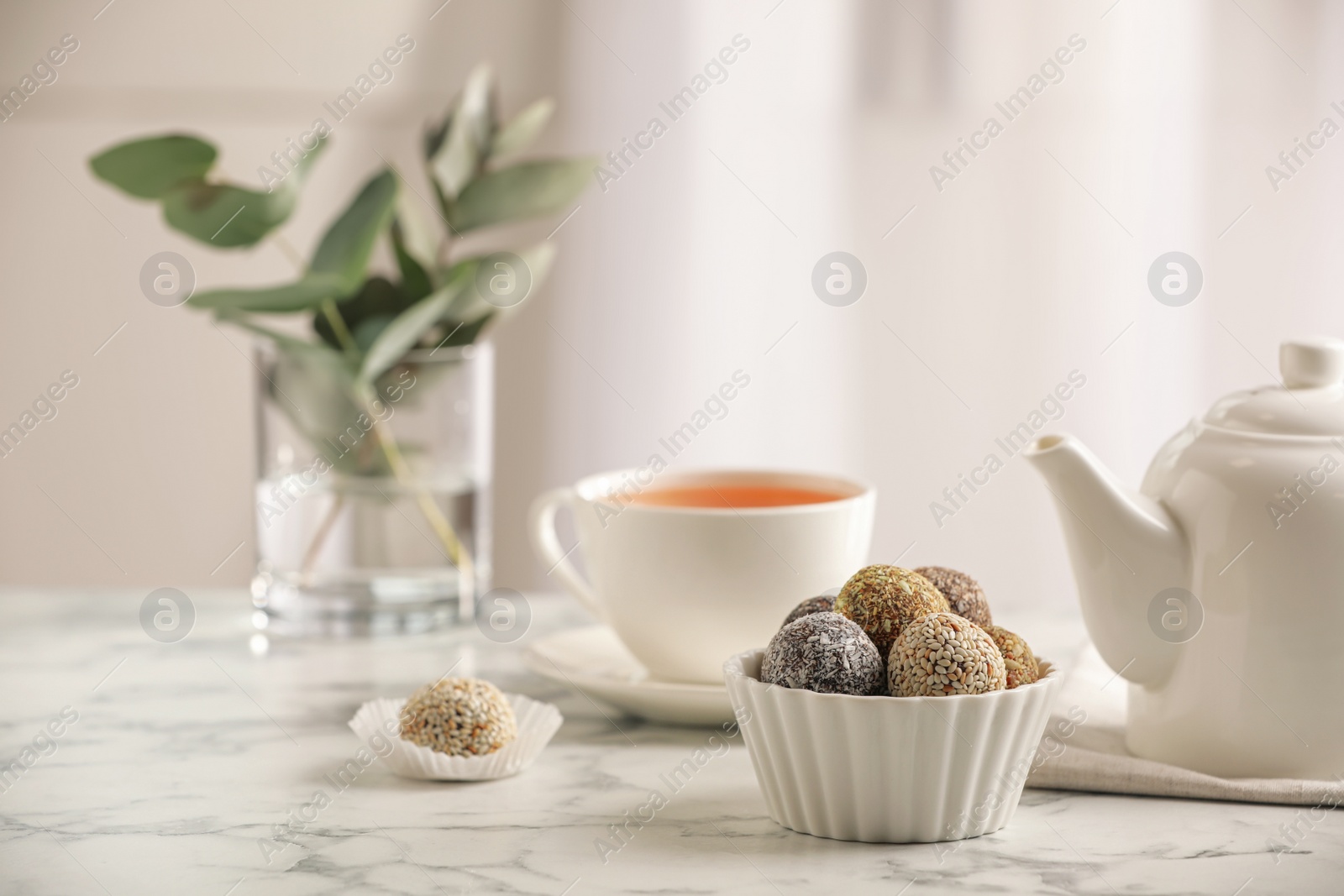 Photo of Different delicious vegan candy balls on white marble table indoors