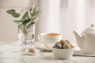 Photo of Different delicious vegan candy balls on white marble table indoors