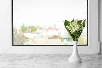 Beautiful lily of the valley bouquet in vase on windowsill, space for text