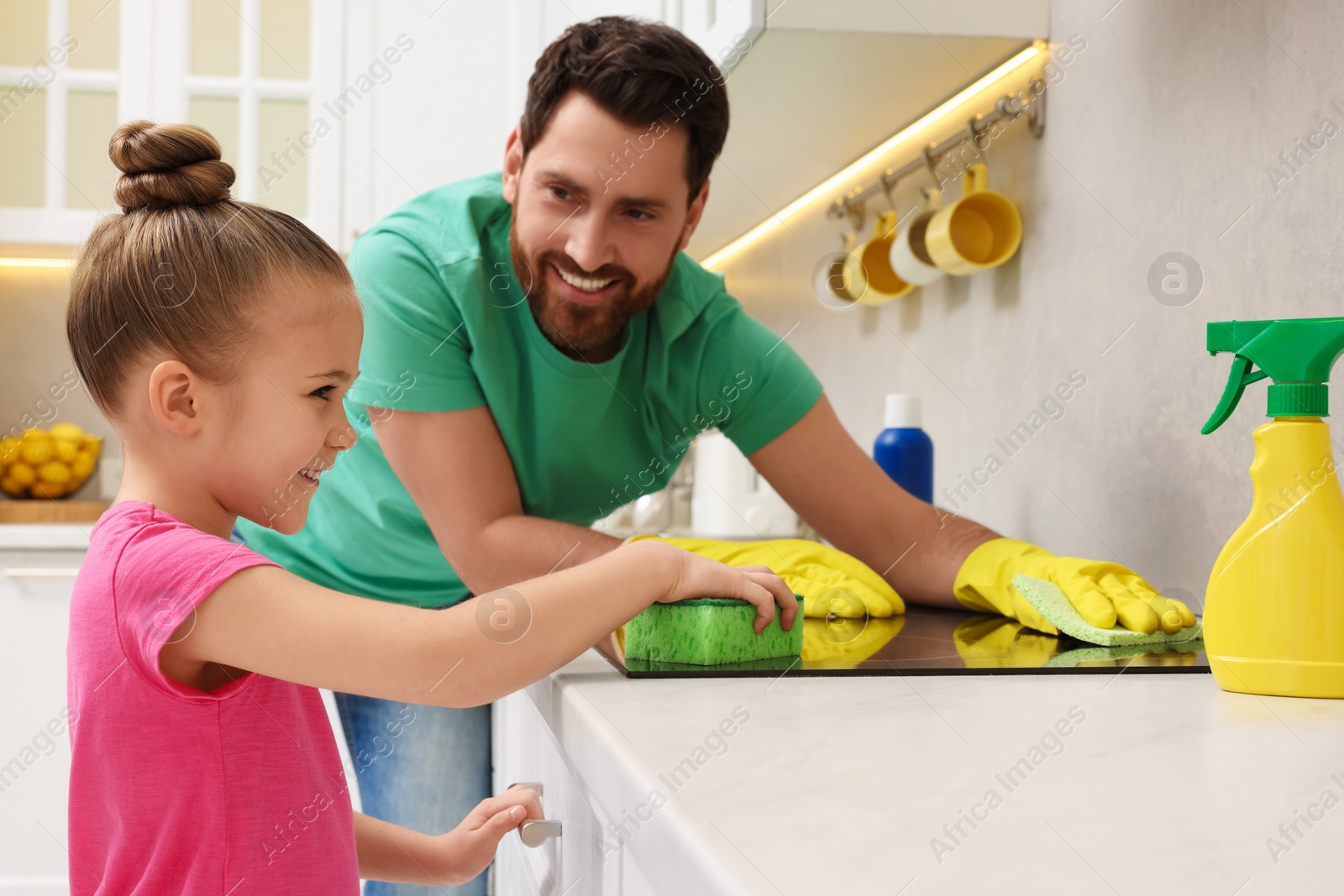 Photo of Spring cleaning. Father and daughter tidying up stove in kitchen together