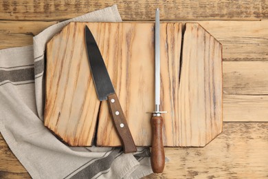 Photo of Sharpening steel and knife on wooden table, top view