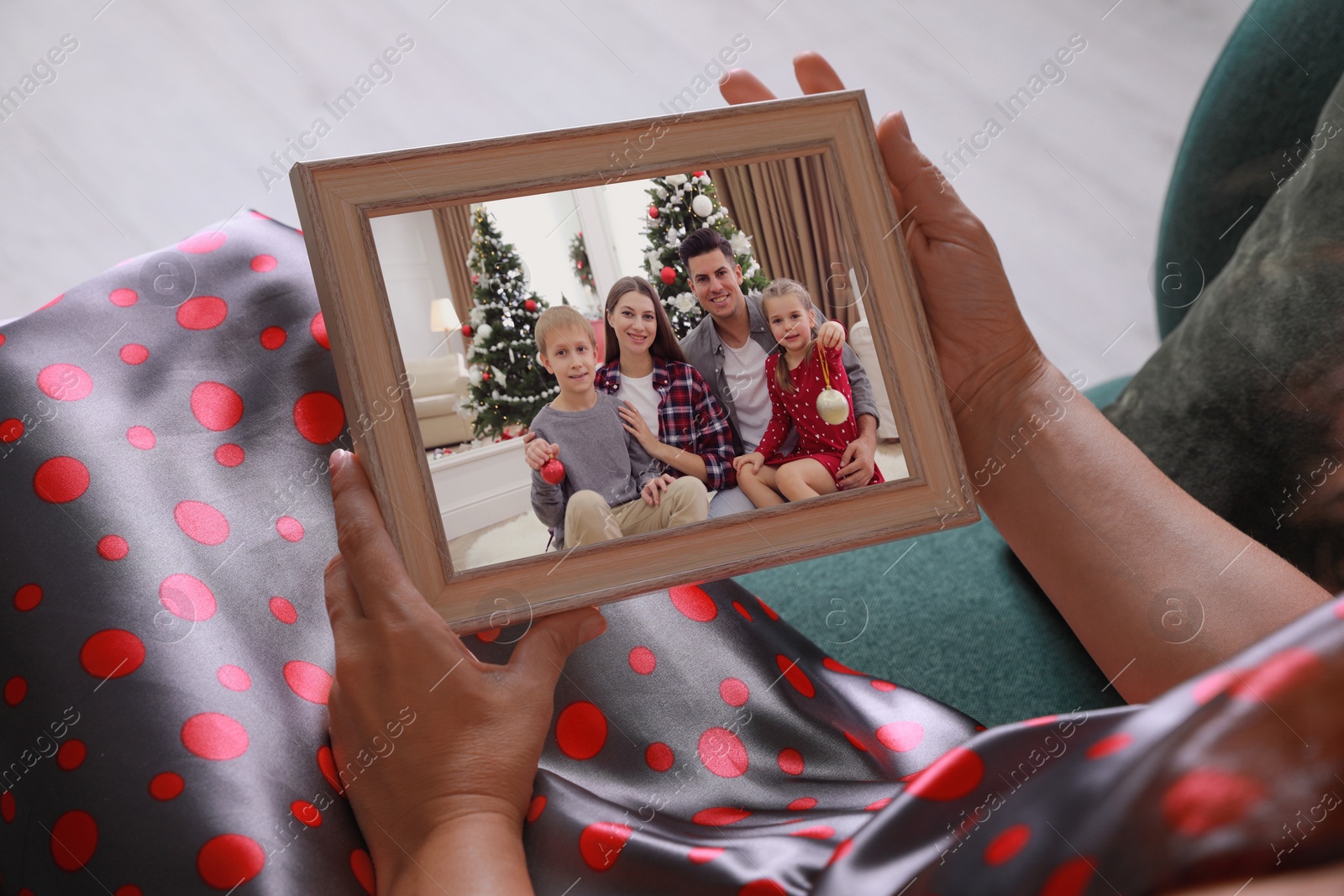 Image of Woman holding frame with photo portrait of her family indoors, closeup