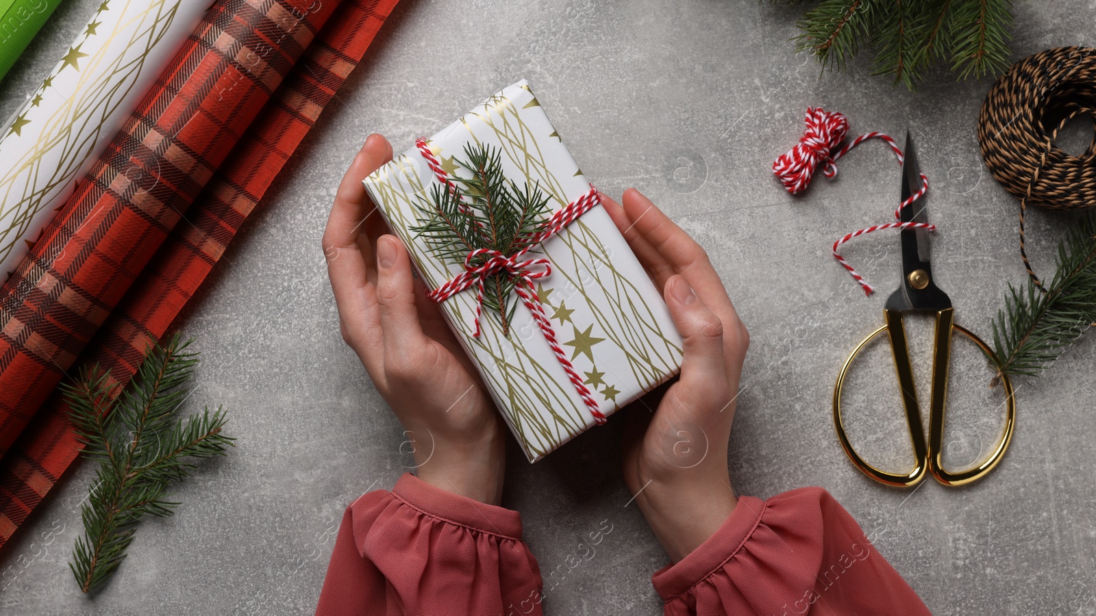 Photo of Woman with Christmas gift at grey stone table, top view