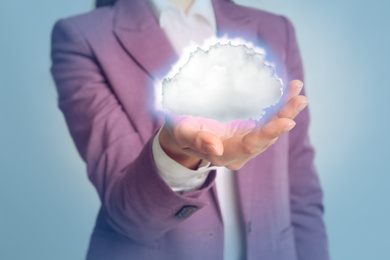 Image of Young woman holding cloud against light grey background, focus on hand. Modern technology