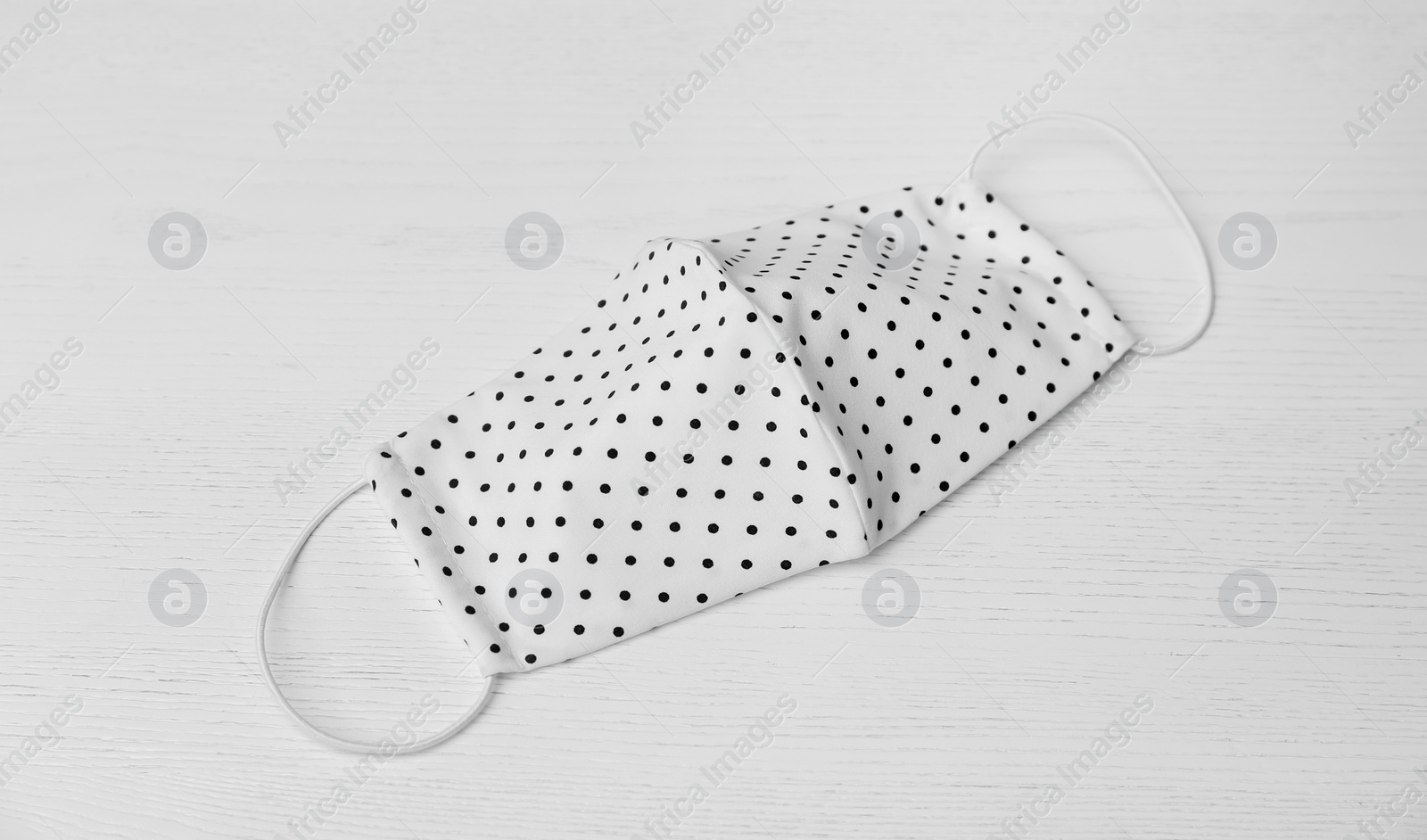 Photo of Handmade cloth mask on white wooden background. Personal protective equipment during COVID-19 pandemic