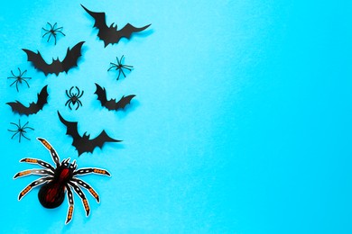 Photo of Flat lay composition with paper bats and spiders on light blue background, space for text. Halloween decor