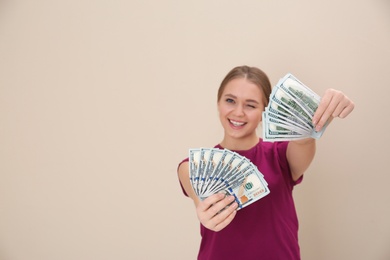 Portrait of happy young woman with money on color background. Space for text