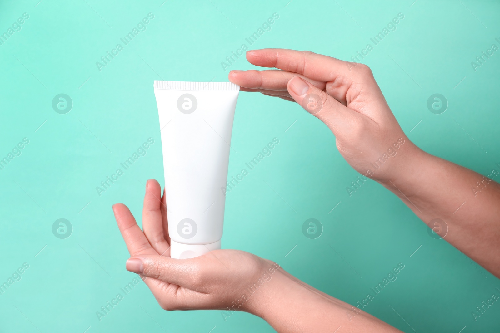 Photo of Woman with tube of hand cream on turquoise background, closeup