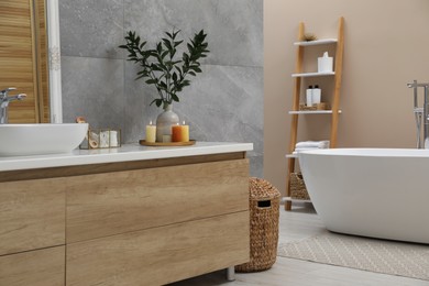 Beautiful plant in vase and burning candles near vessel sink on bathroom vanity