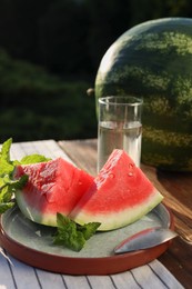 Photo of Slices of tasty ripe watermelon on wooden table outdoors