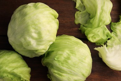 Fresh green iceberg lettuce heads and leaves on wooden table, flat lay