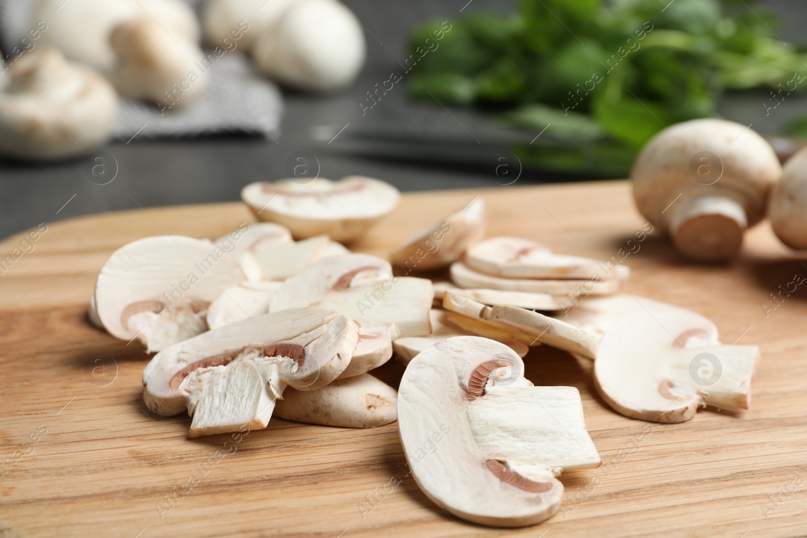 Photo of Wooden board with sliced raw mushrooms on table, closeup