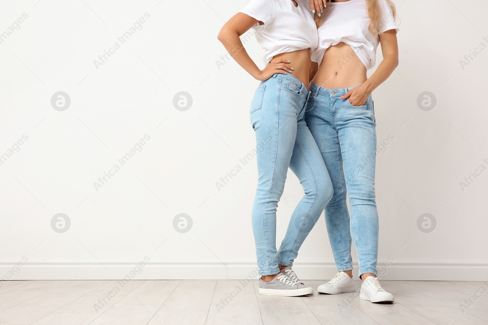 Photo of Group of young women in jeans near light wall