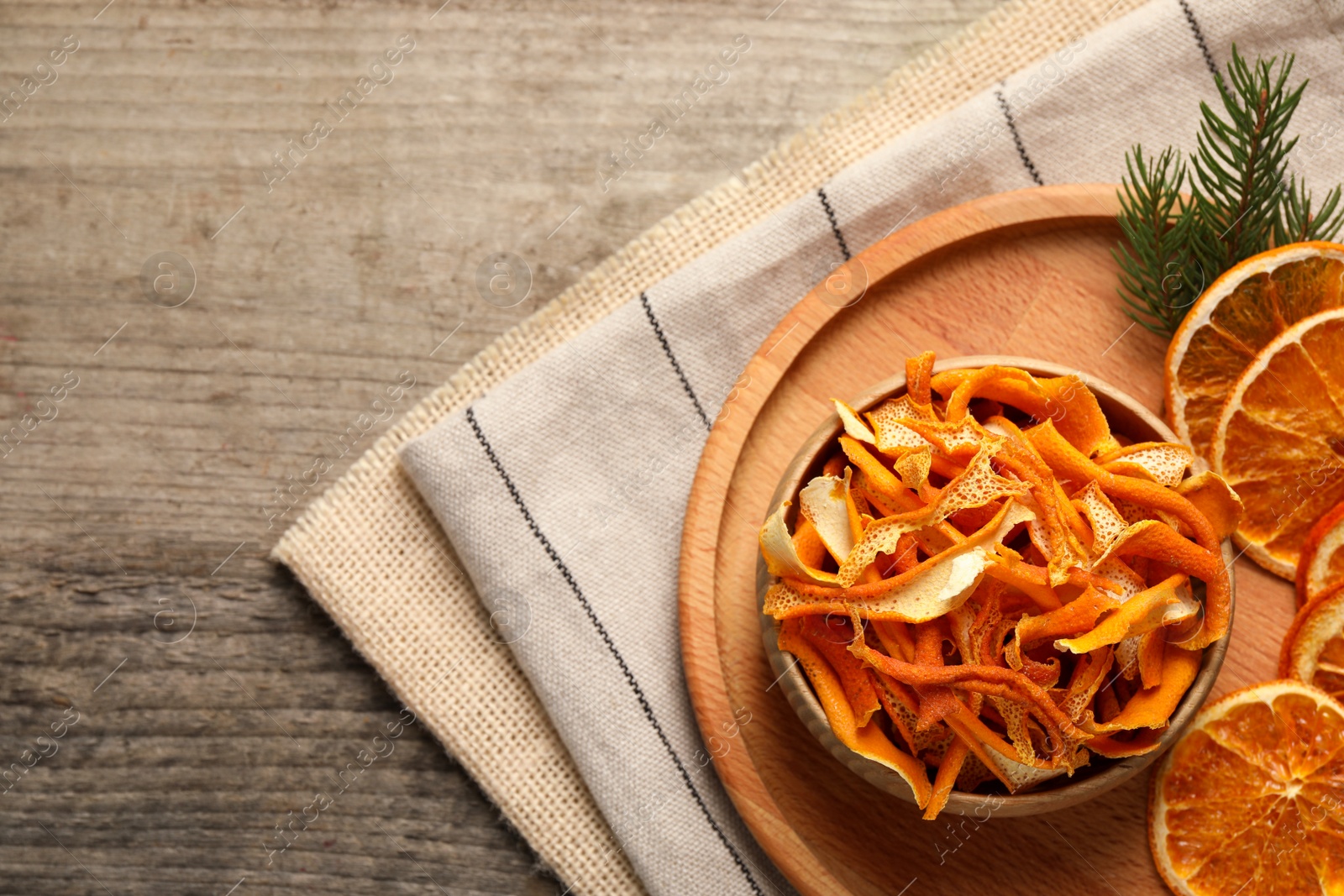 Photo of Dry orange peels and slices on wooden table, top view. Space for text