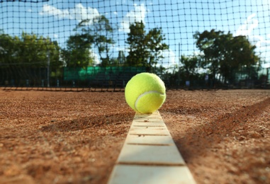 Photo of Bright yellow tennis ball on clay court