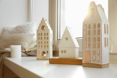 Photo of Beautiful house shaped candle holders on windowsill indoors