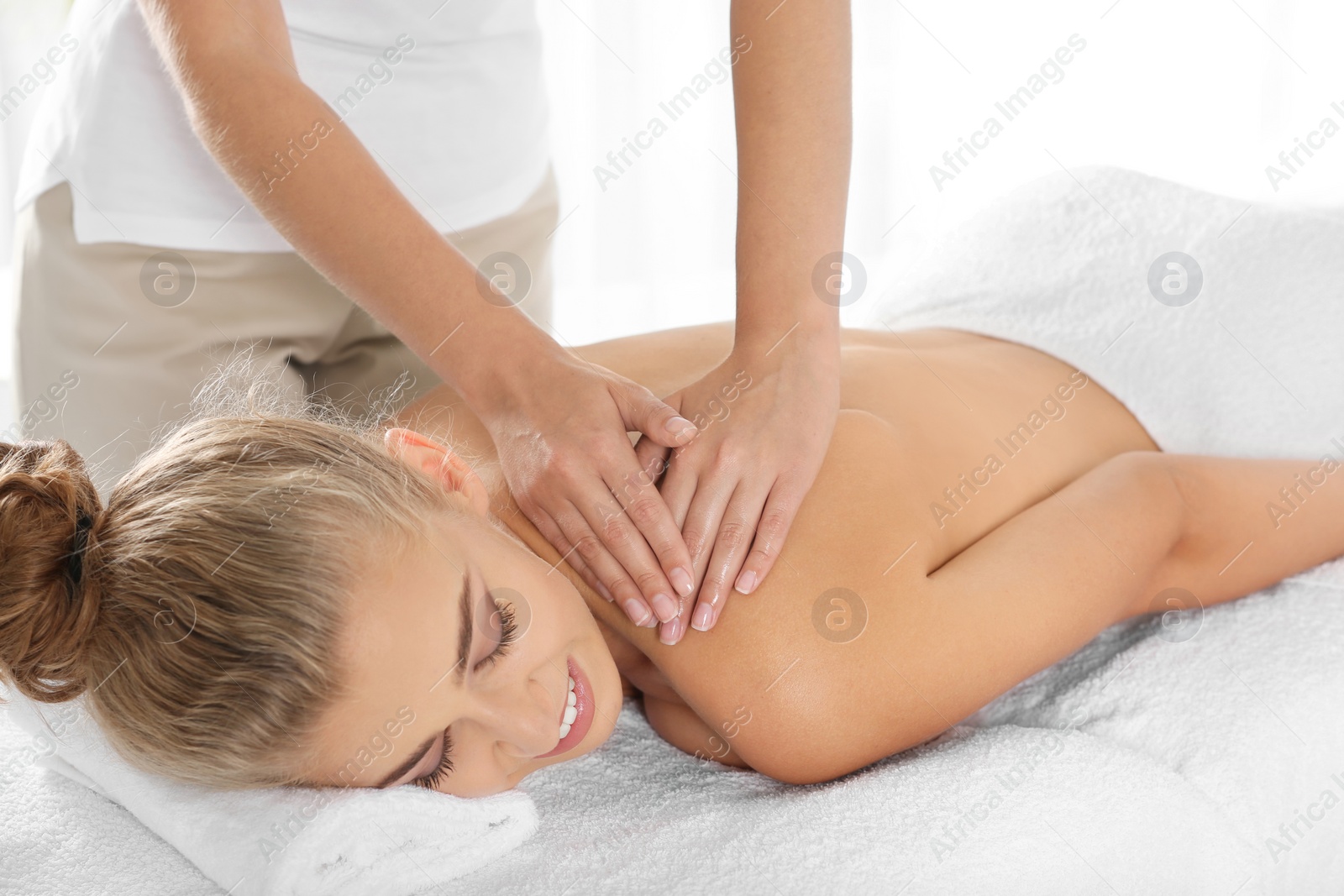 Photo of Relaxed woman receiving shoulders massage in wellness center